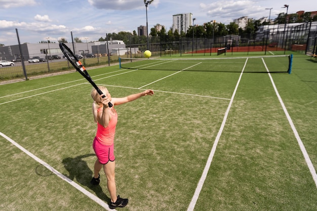 Bonita deportista con raqueta en la cancha de tenis. Estilo de vida saludable