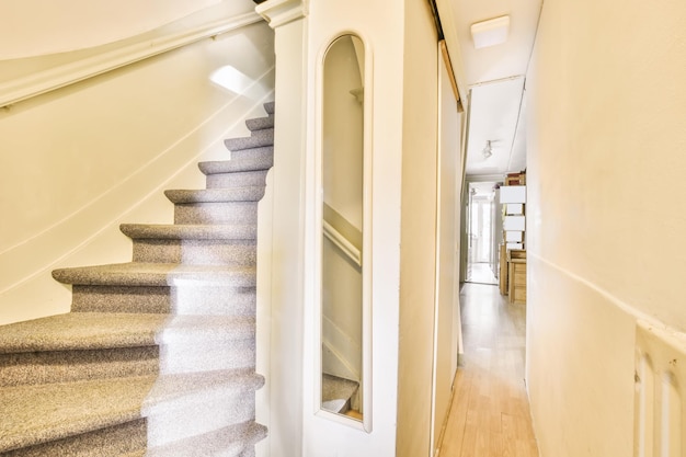 Bonita escalera con alfombra gris y paredes blancas.