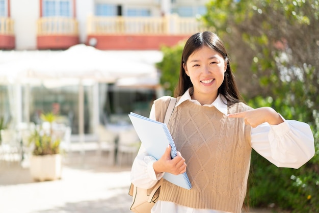 Bonita estudiante china al aire libre con expresión facial sorpresa