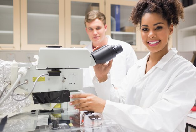 Bonita estudiante de ciencia utilizando microscopio