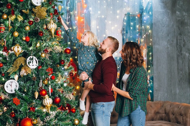 Bonita familia está decorando un árbol de Navidad