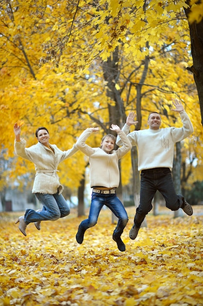 Bonita familia feliz saltando en el parque de otoño