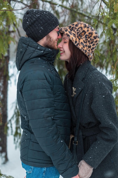 Bonita felicidad joven belleza pareja de amantes en ropa de invierno se divierten y se abrazan al aire libre en el parque de nieve de invierno