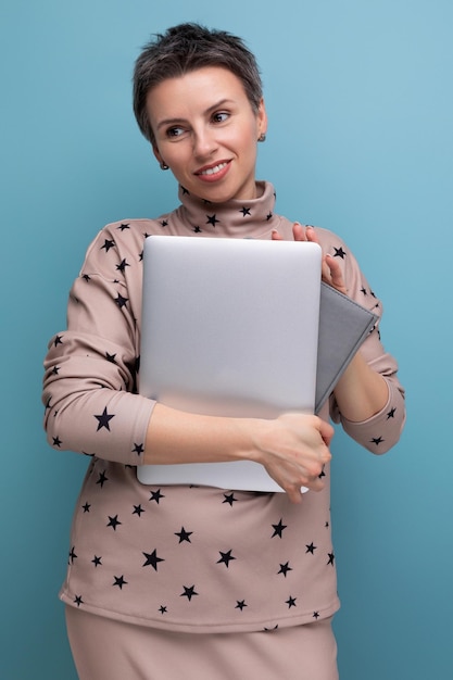 Bonita jovem empresária europeia com cabelo escuro curto segurando um laptop