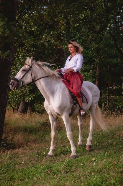 Bonita jovem feliz a cavalo no parque de verão