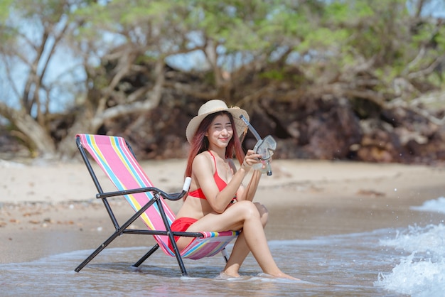 Bonita jovem mulher asiática em biquíni na bela praia nas férias de verão na Tailândia