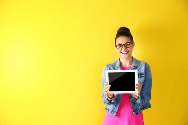 Foto bonita jovem segurando o tablet em fundo amarelo