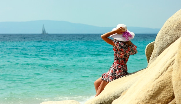 Bonita joven con un sombrero en la orilla del mar