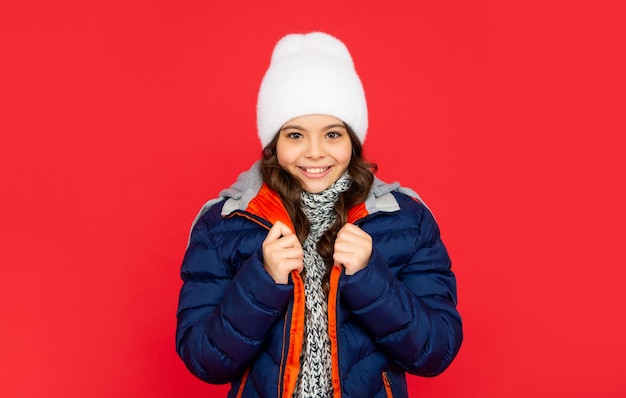 Bonita jovencita sobre fondo rojo retrato de niño vistiendo ropa de abrigo con bufanda