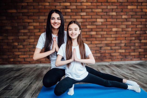 de bonita madre e hija haciendo gimnasia y estiramientos en casa. Estilo de vida saludable familiar.