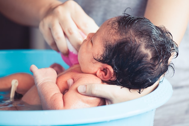 Bonita menina recém nascida asiática toma um banho na banheira