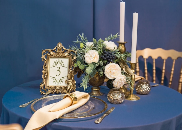 Bonita mesa de boda y decoración de boda con cubiertos en tonos dorados y azul marino.