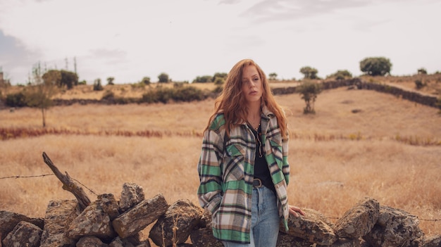 Una bonita modelo posa con un campo en su fondo