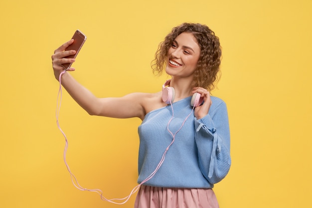 Bonita modelo posando con auriculares rosa y teléfono.