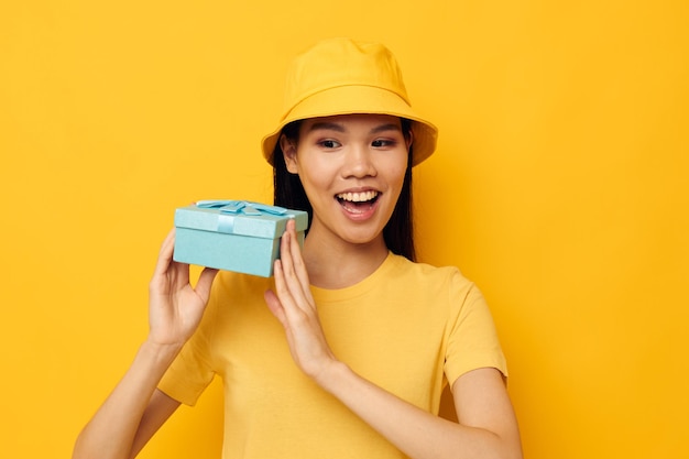 Bonita morena con una camiseta amarilla y un sombrero con un modelo de estudio de regalo inalterado