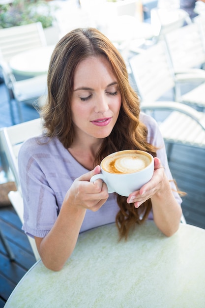 Bonita morena disfrutando de un capuchino