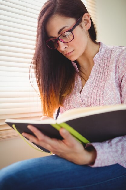 Bonita morena estudiando al lado de la ventana