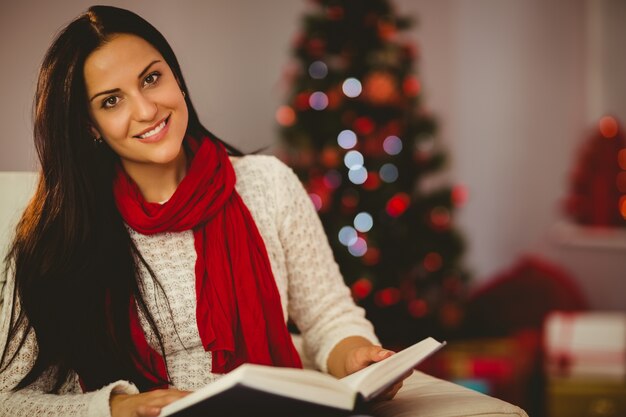 Bonita morena leyendo en el sofá en Navidad