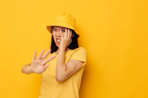 Bonita morena con un sombrero amarillo posando emociones fondo amarillo inalterado