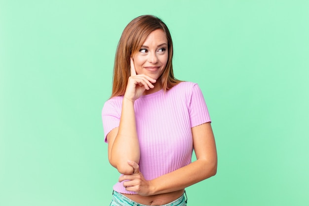 Bonita mujer adulta sonriendo con una expresión feliz y segura con la mano en la barbilla