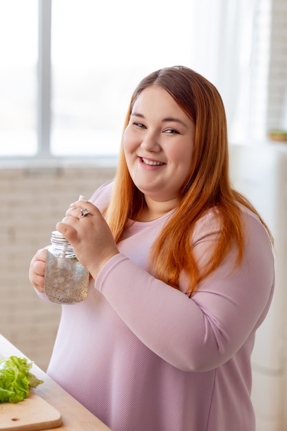 Bonita mujer alegre sonriendo mientras toma un delicioso batido