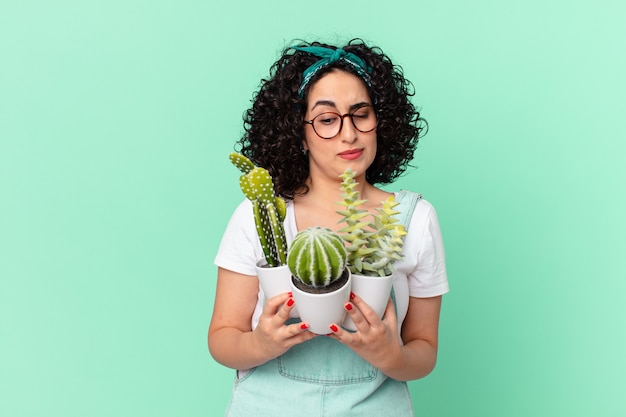 Bonita mujer árabe con cactus en macetas decorativas