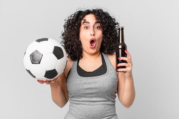 Bonita mujer árabe con una pelota de fútbol y una cerveza