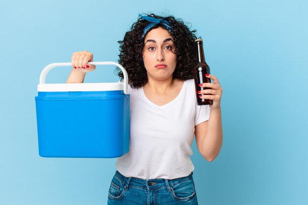 Bonita mujer árabe con un refrigerador portátil y una cerveza