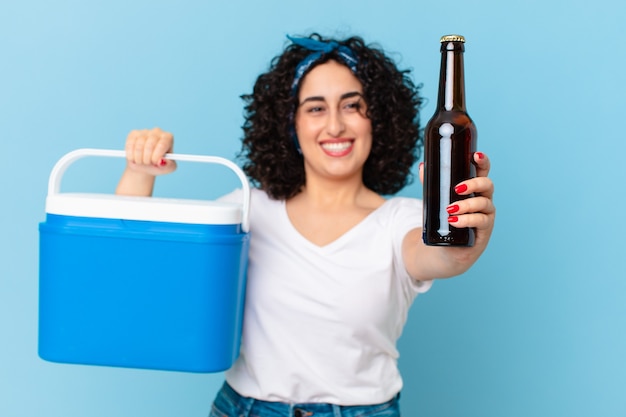 Foto bonita mujer árabe con un refrigerador portátil y una cerveza