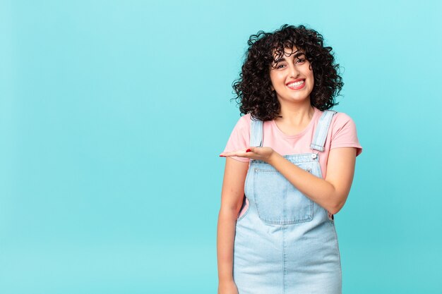 Bonita mujer árabe sonriendo alegremente, sintiéndose feliz y mostrando un concepto