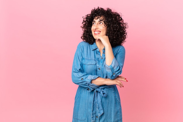 Bonita mujer árabe sonriendo felizmente y soñando despierto o dudando