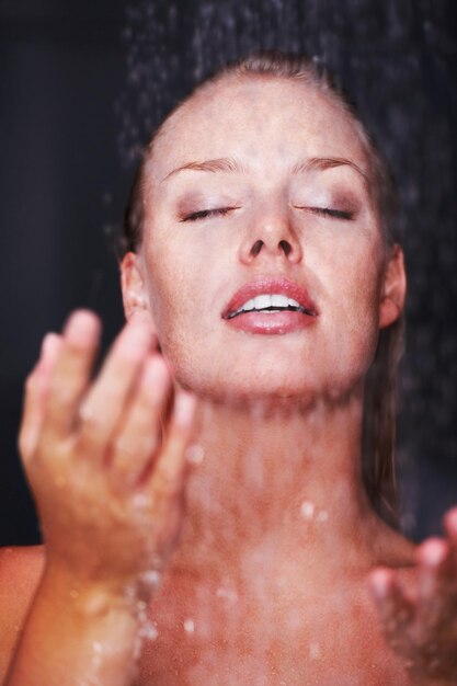 Bonita mujer caucásica bañándose bajo una ducha Higiene Primer plano de una bonita mujer caucásica bajo una ducha fondo oscuro