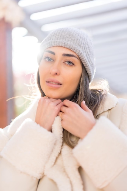 Bonita mujer caucásica con gorro de lana en un parque de la ciudad al atardecer estilo de vida invernal