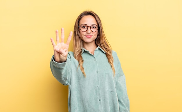 bonita mujer caucásica sonriendo y luciendo amistosa, mostrando el número cuatro o cuarto con la mano hacia adelante, contando hacia atrás