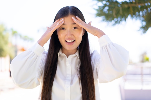 Bonita mujer china al aire libre con expresión de sorpresa