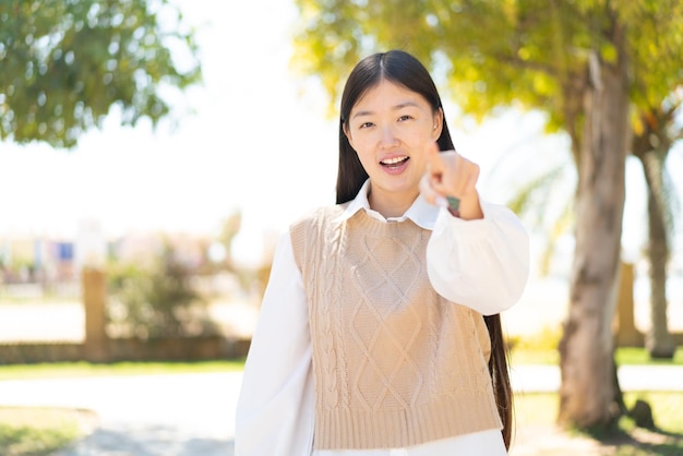 Bonita mujer china al aire libre sorprendida y apuntando al frente