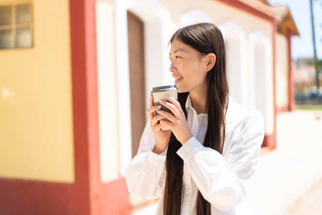 Bonita mujer china al aire libre sosteniendo un café para llevar