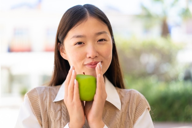 Bonita mujer china al aire libre sosteniendo una manzana