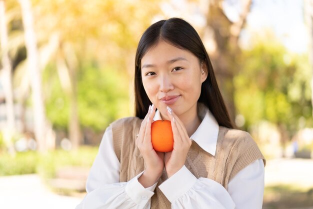 Bonita mujer china al aire libre sosteniendo una naranja