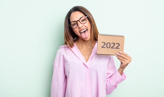 Bonita mujer hispana con actitud alegre y rebelde, bromeando y sacando la lengua. Concepto de calendario 2022