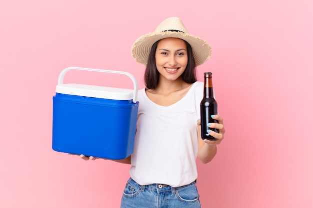 Bonita mujer hispana con un congelador portátil y una cerveza