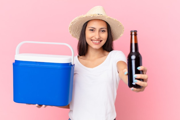 Bonita mujer hispana con un congelador portátil y una cerveza