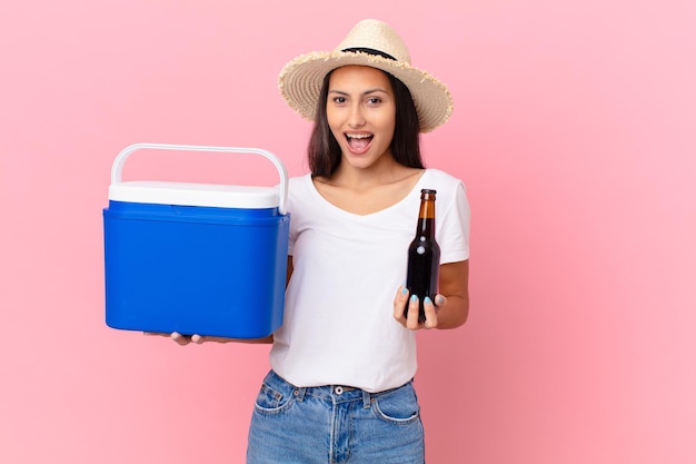 Bonita mujer hispana con un congelador portátil y una cerveza