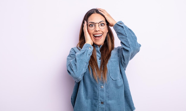 Bonita mujer hispana levantando las manos a la cabeza, con la boca abierta, sintiéndose extremadamente afortunada, sorprendida, emocionada y feliz