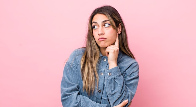 Foto bonita mujer hispana con una mirada concentrada preguntándose con una expresión dudosa mirando hacia arriba y hacia un lado