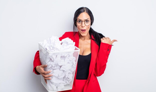 Foto bonita mujer hispana mirando asombrado en concepto de basura de bolas de papel de incredulidad