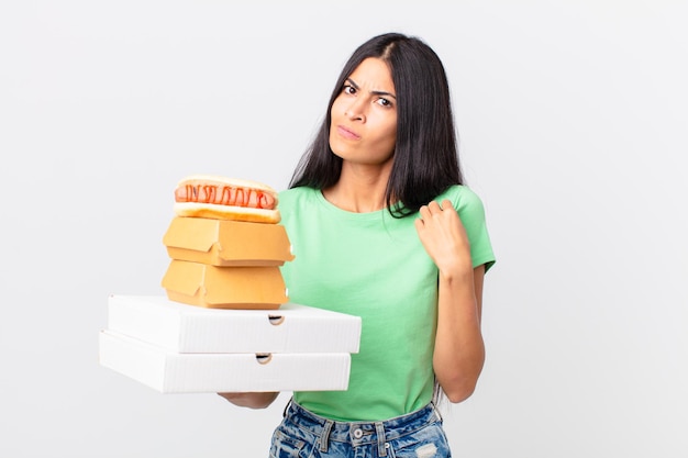 Bonita mujer hispana que parece arrogante, exitosa, positiva y orgullosa y sostiene cajas de comida rápida para llevar