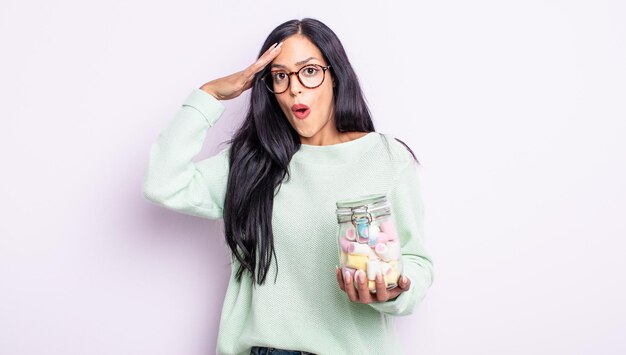 Bonita mujer hispana que parece feliz, asombrada y sorprendida concepto de caramelos de gelatina