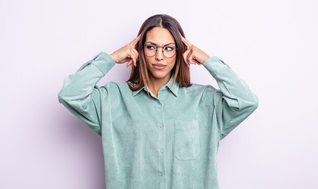 Foto bonita mujer hispana que se siente confundida o dudando, concentrándose en una idea, pensando mucho, buscando copiar el espacio en el costado