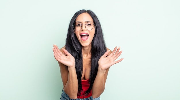 Bonita mujer hispana que se siente conmocionada y emocionada, riendo, asombrada y feliz debido a una sorpresa inesperada.